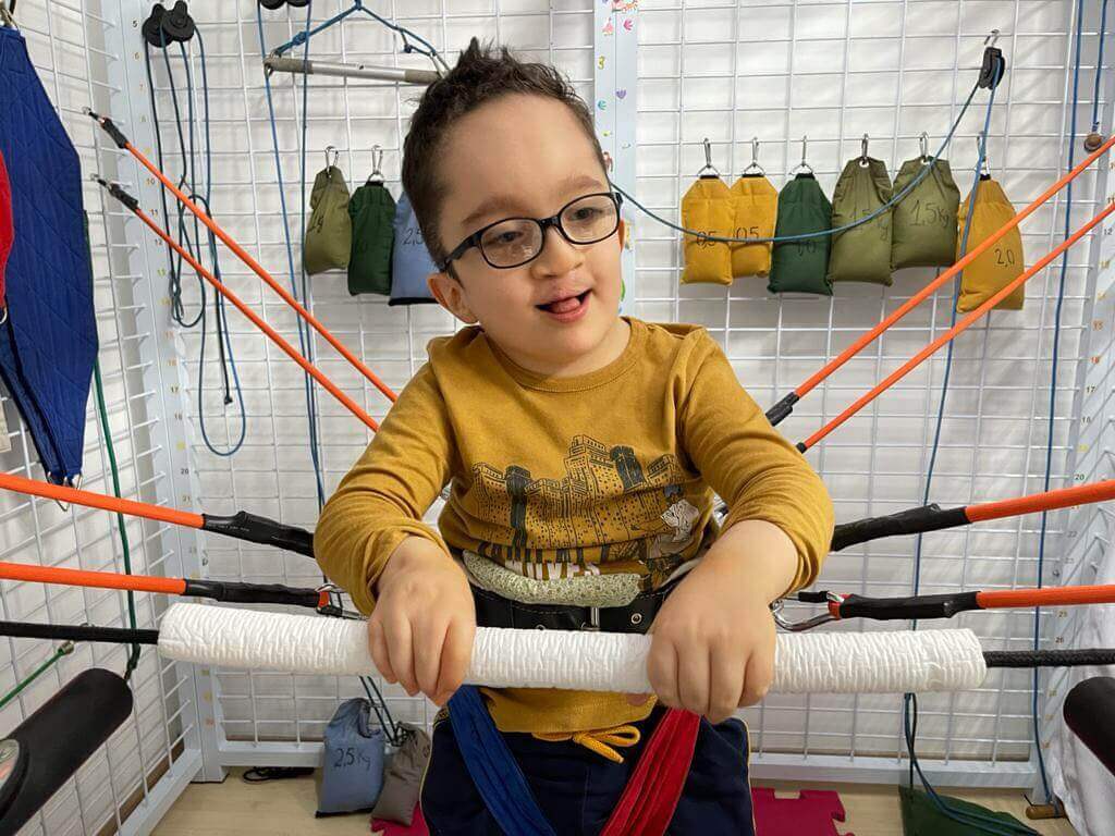 Foto de um menino com a Síndrome de Gorli-Goltz durante uma sessão de fisioterapia